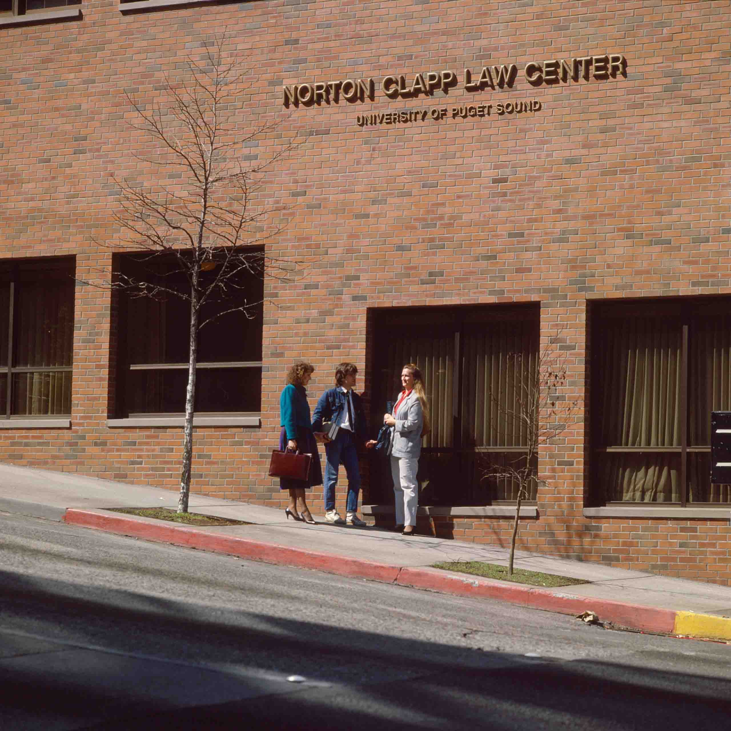 Three people in conversation outside of the Norton Clapp Law Center