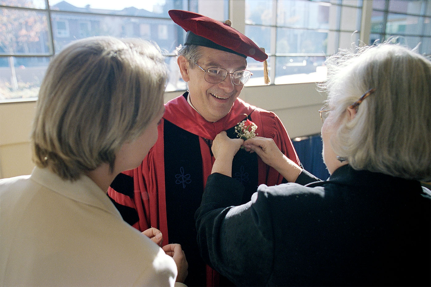 A faculty member getting a boutonniere (floral decoration) pinned to his gown at the Sullivan Hall Dedication Ceremony (1999)