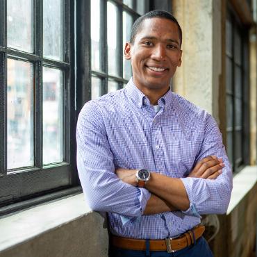 Efrain Hudnell leaning against a wall with a window