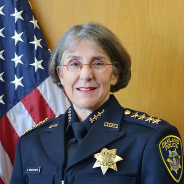Anne Kirkpatrick '89 in a police uniform in front of an American flag