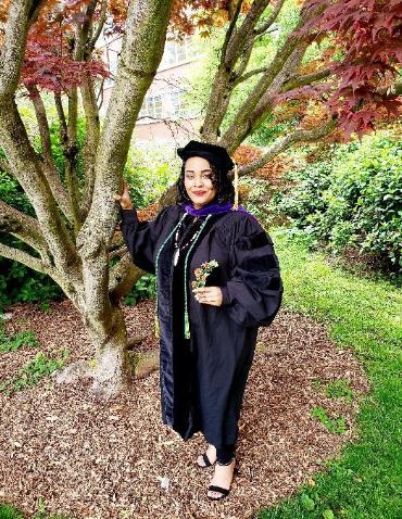 Brittany Jones standing near Sullivan Hall with graduation gown.