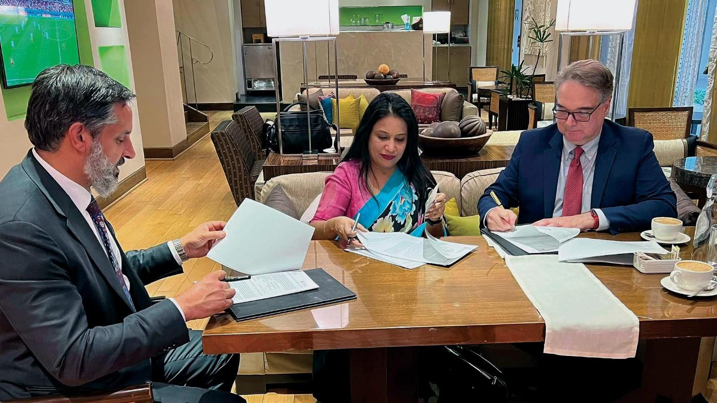 University administrators sit at a table and sign documents