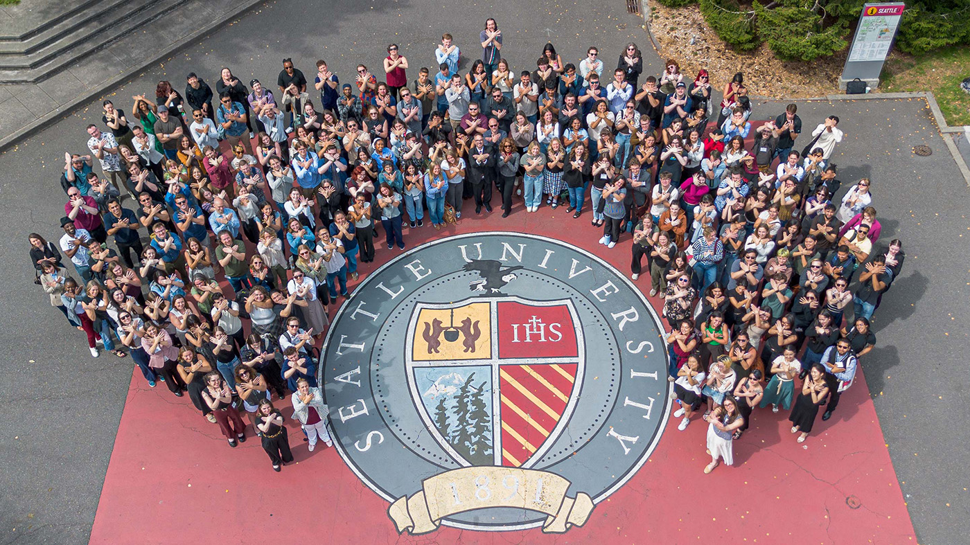Students standing in a group around Seattle University's seal