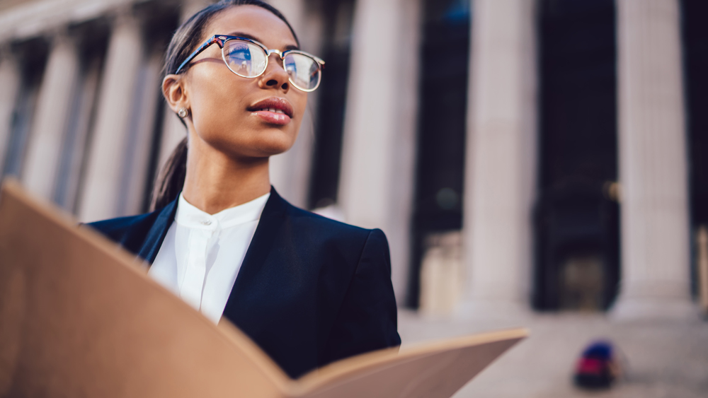 A woman standing in front of a legal institution with an open notebook