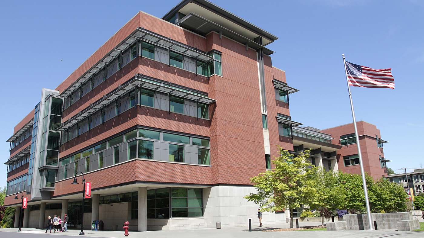 Exterior of the Sullivan Hall building on the Seattle University campus with American flag on a flagpole blowing in the wind